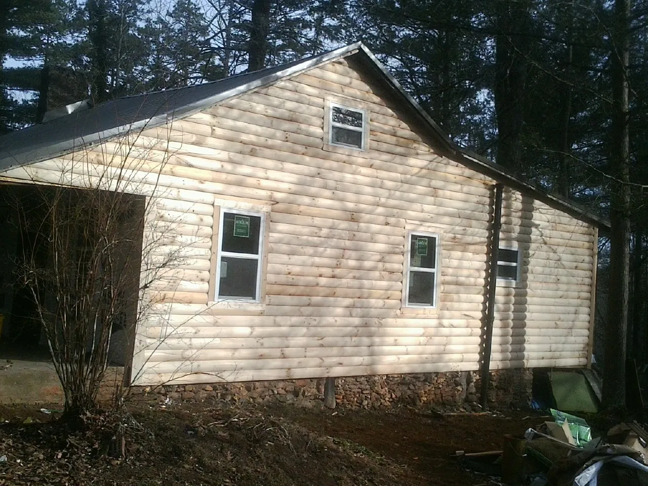 New log siding and dark metal roofing on a gable end in Cataumet