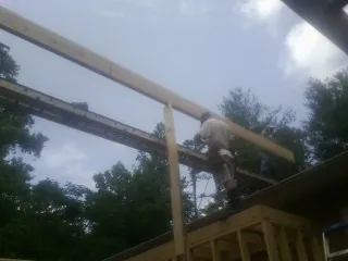 Carpenter setting a ridge beam over a new addition frame — Ice Dam Removal by Roofing Brothers in Cataumet