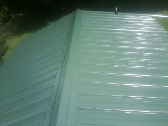 New green metal panels meeting at the ridge of a roof — Flat Roof Repair work by our crew in Cataumet