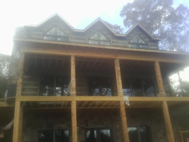 Dormers and porch framing on a large log home under construction — Roof Coating work by our crew in Cataumet