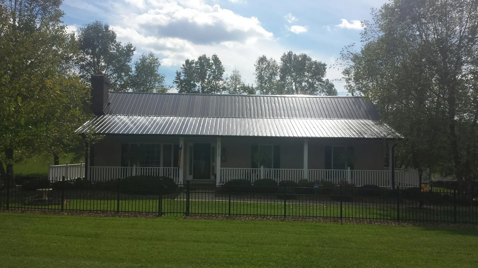 Gray metal roof on a brick ranch with a full width front porch — Gutter Guard Installation work by our crew in Cataumet